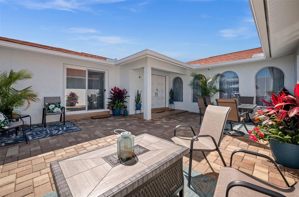 A paved patio features outdoor furniture, potted plants, and a sliding glass door entrance — 1432 VENETIAN COURT, CAPE CORAL, FL