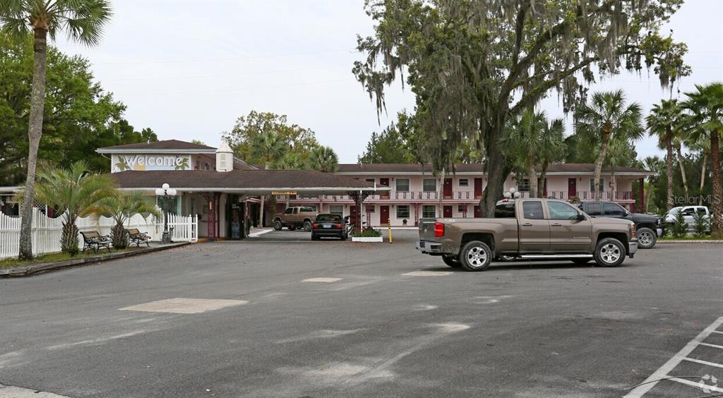 A two-story motel exterior features a covered entrance, parking lot, and surrounding palm trees — 16872 SE HIGHWAY 19, CROSS CITY, FL