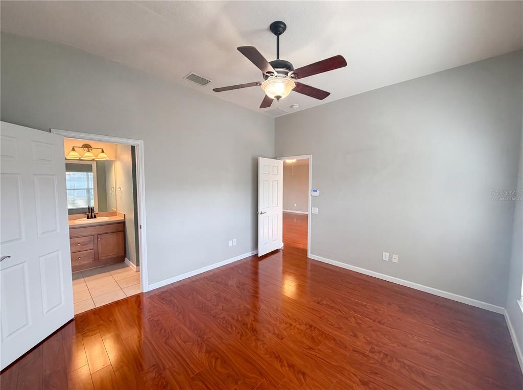 An empty bedroom with hardwood floors, a ceiling fan, and an attached bathroom — 575 SEA HOLLY DRIVE, BROOKSVILLE, FL