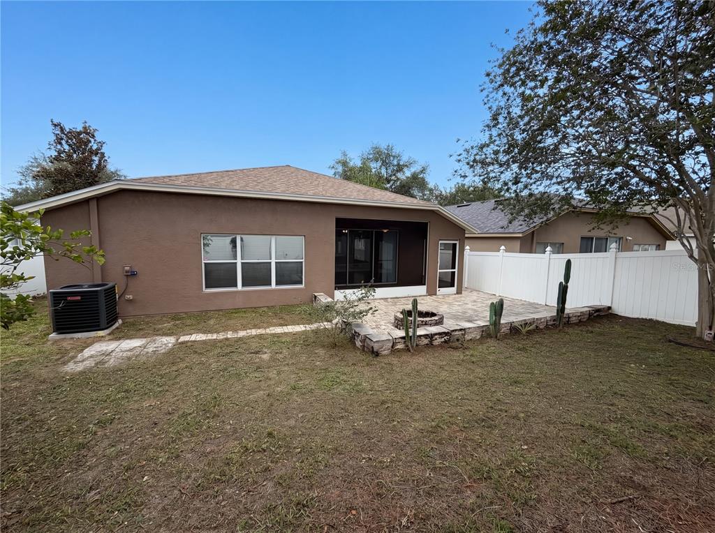 The backyard features a paved patio with a fire pit, a screened porch, and fencing — 575 SEA HOLLY DRIVE, BROOKSVILLE, FL