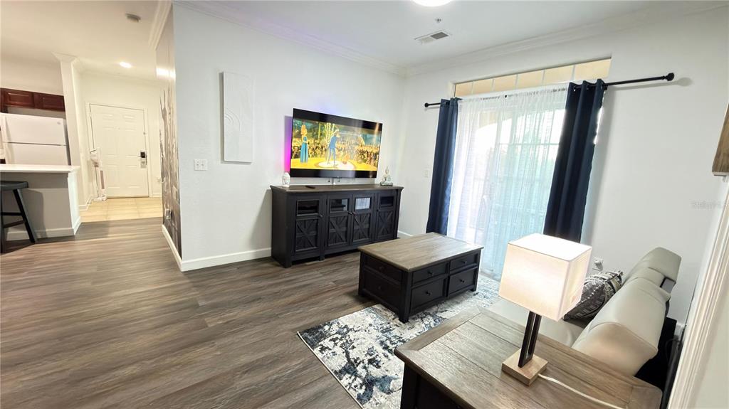 A living room features wood-look flooring, a dark media console, a coffee table, and sliding doors — 1301 TUSCAN TERRACE UNIT 9403, DAVENPORT, FL