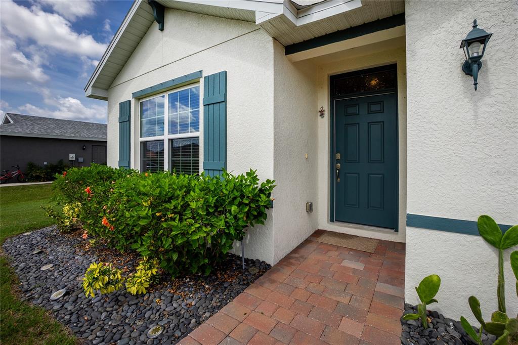 The exterior of a house features a teal door, blue shutters, and a brick walkway — 341 PORTO ALEGRE STREET, PUNTA GORDA, FL