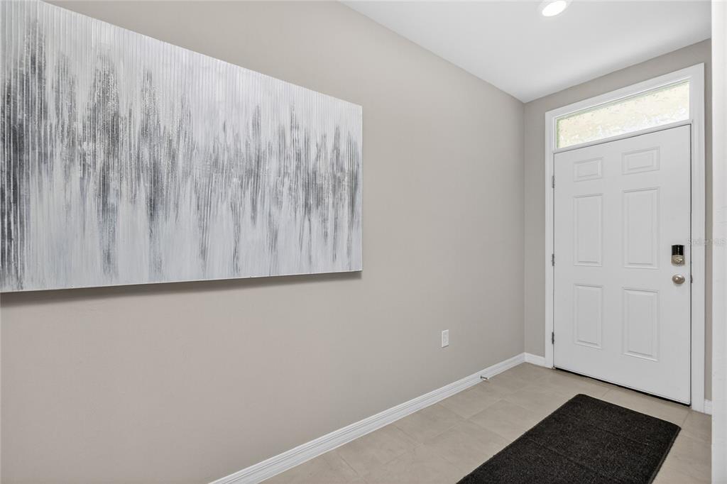 An entryway features light gray walls, a large abstract painting, and a white front door — 341 PORTO ALEGRE STREET, PUNTA GORDA, FL
