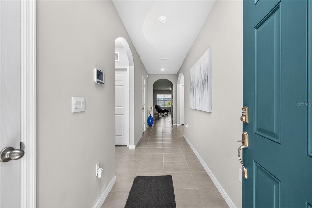 A view from an open teal front door into a tiled hallway with arched doorways — 341 PORTO ALEGRE STREET, PUNTA GORDA, FL