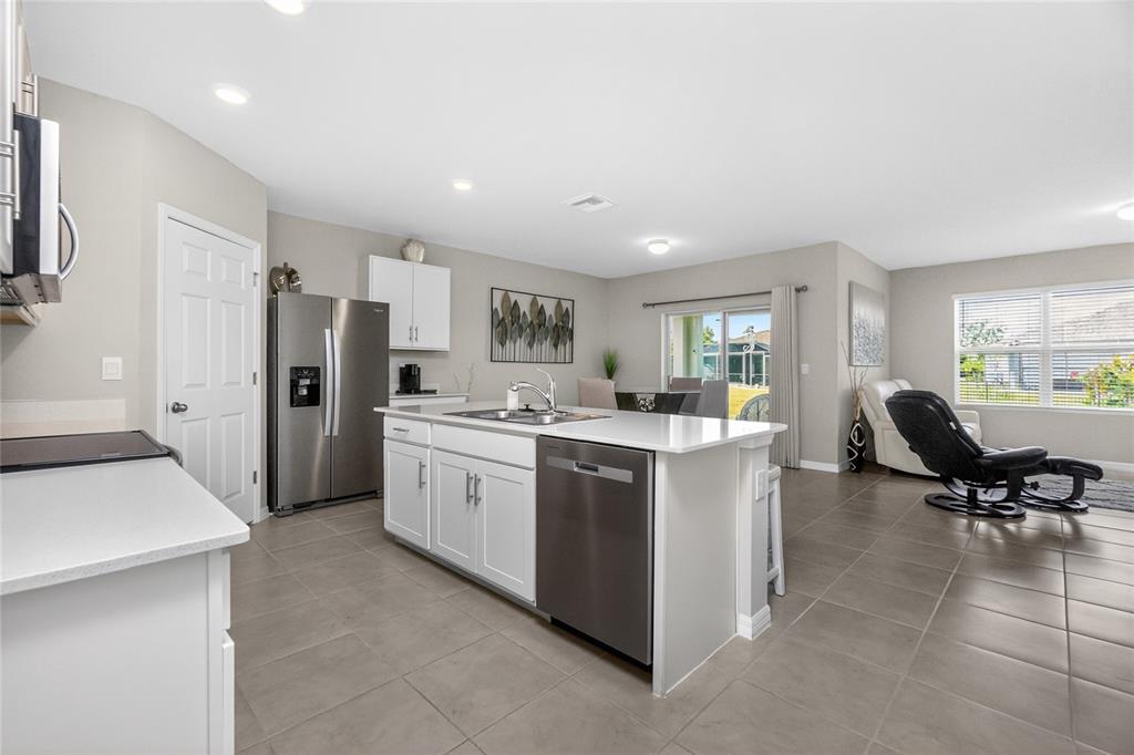 A kitchen with white cabinets, stainless steel appliances, and an island opens to a living area — 341 PORTO ALEGRE STREET, PUNTA GORDA, FL