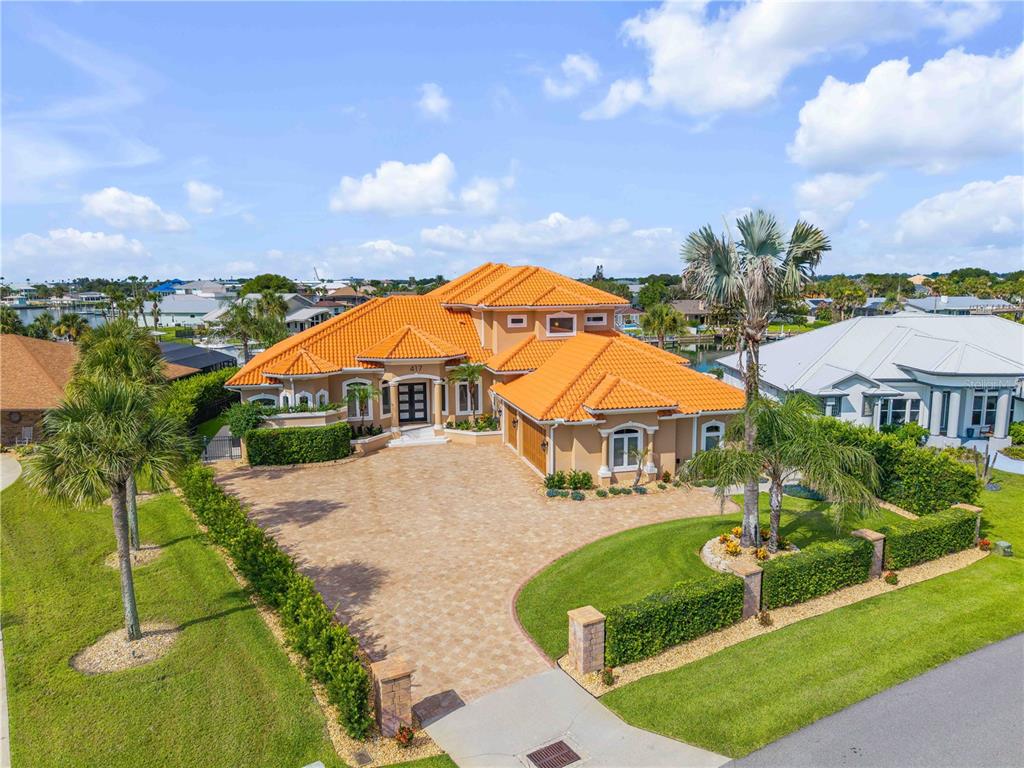 An aerial view shows a tan house with an orange tile roof and paved driveway — 417 QUAY ASSISI, NEW SMYRNA BEACH, FL