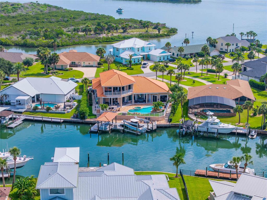 An aerial view shows waterfront houses with pools, private docks, and boats along a canal — 417 QUAY ASSISI, NEW SMYRNA BEACH, FL