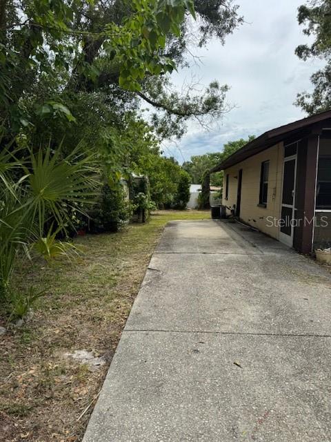 A concrete driveway runs alongside the side of a house toward a grassy backyard — 8609 N 13TH STREET, TAMPA, FL