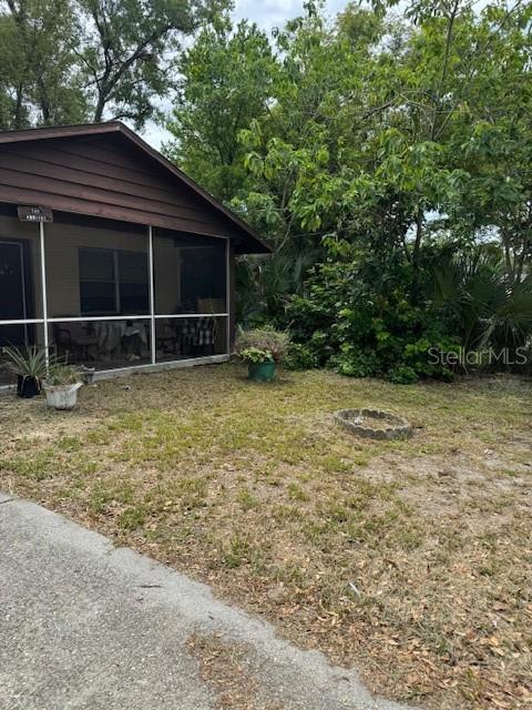 A brown house with a screened-in porch sits next to a yard with trees — 8609 N 13TH STREET, TAMPA, FL