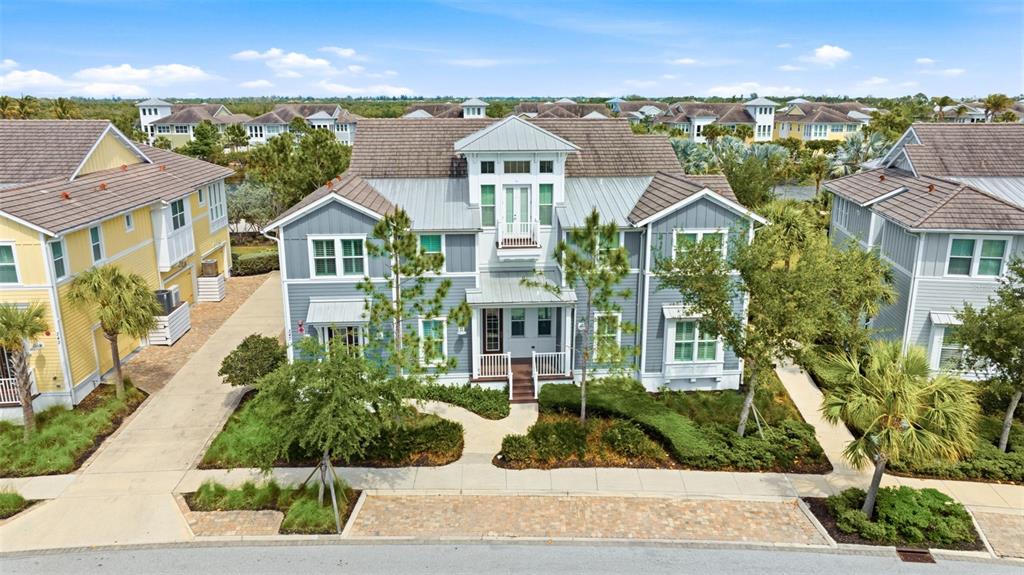 An exterior view of a three-story blue house with a metal roof and landscaping — 347 COMPASS POINT DRIVE UNIT 201, BRADENTON, FL