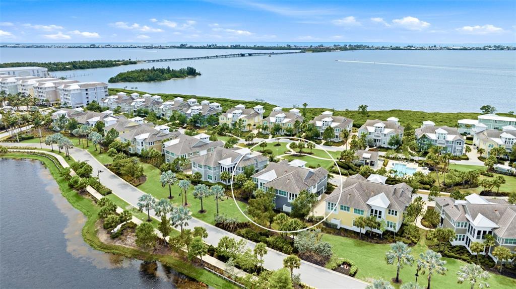 An aerial view shows a multi-story residential building surrounded by lush landscaping and water — 347 COMPASS POINT DRIVE UNIT 201, BRADENTON, FL