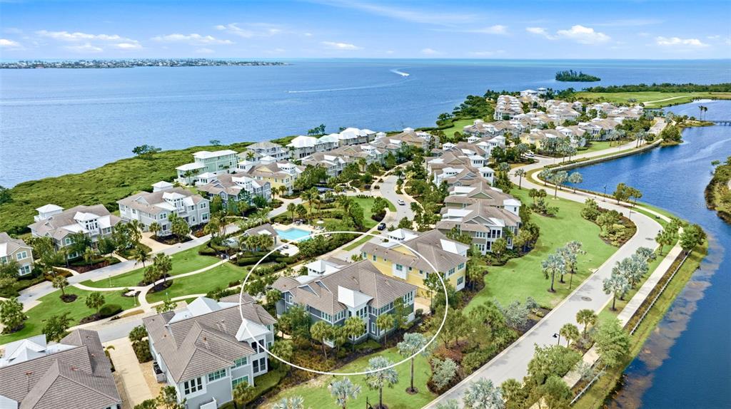 An aerial view shows a multi-story residential building circled in a coastal community — 347 COMPASS POINT DRIVE UNIT 201, BRADENTON, FL