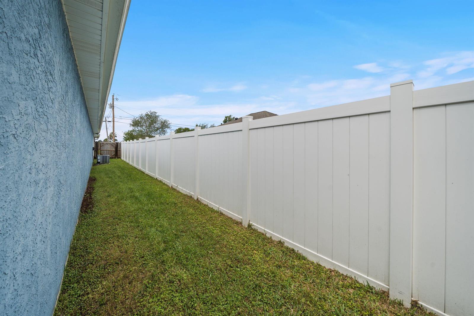 A side yard features a blue stucco wall and a tall white vinyl privacy fence — 1407 Rhode Island Avenue, FL 32444, FL