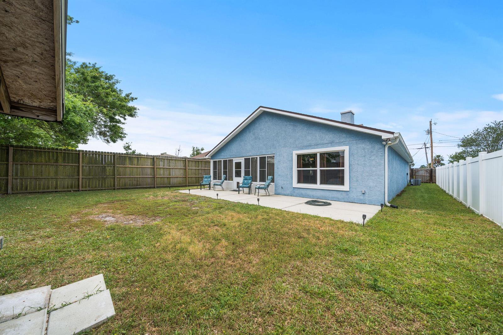 The exterior of a blue stucco house features a concrete patio and a fenced yard — 1407 Rhode Island Avenue, FL 32444, FL