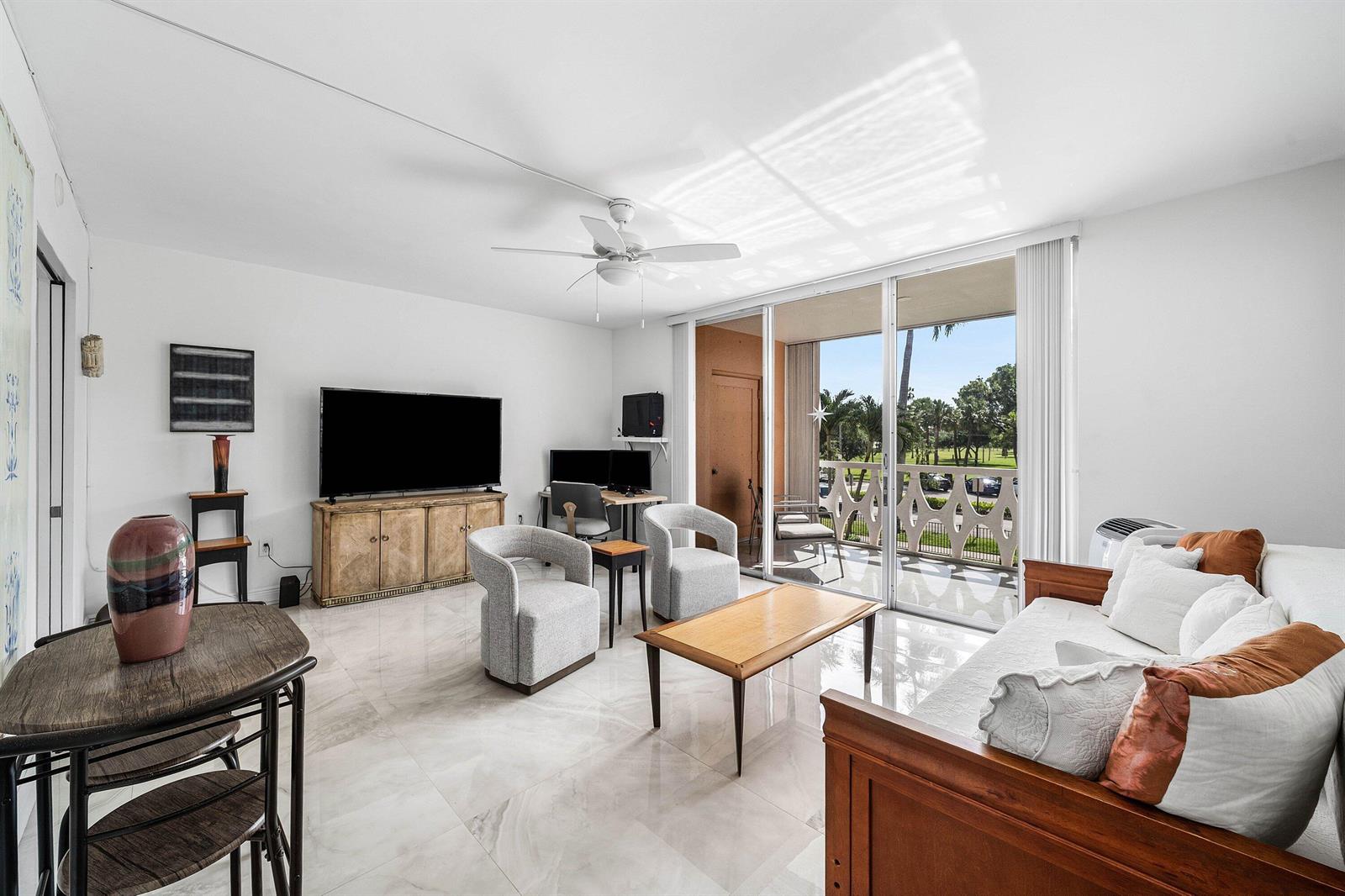 A living room with white tile floors, a wooden sofa, and a balcony overlooking trees — 15 S Golfview Road # 206, Lake Worth FL 33460, LAKE WORTH, FL