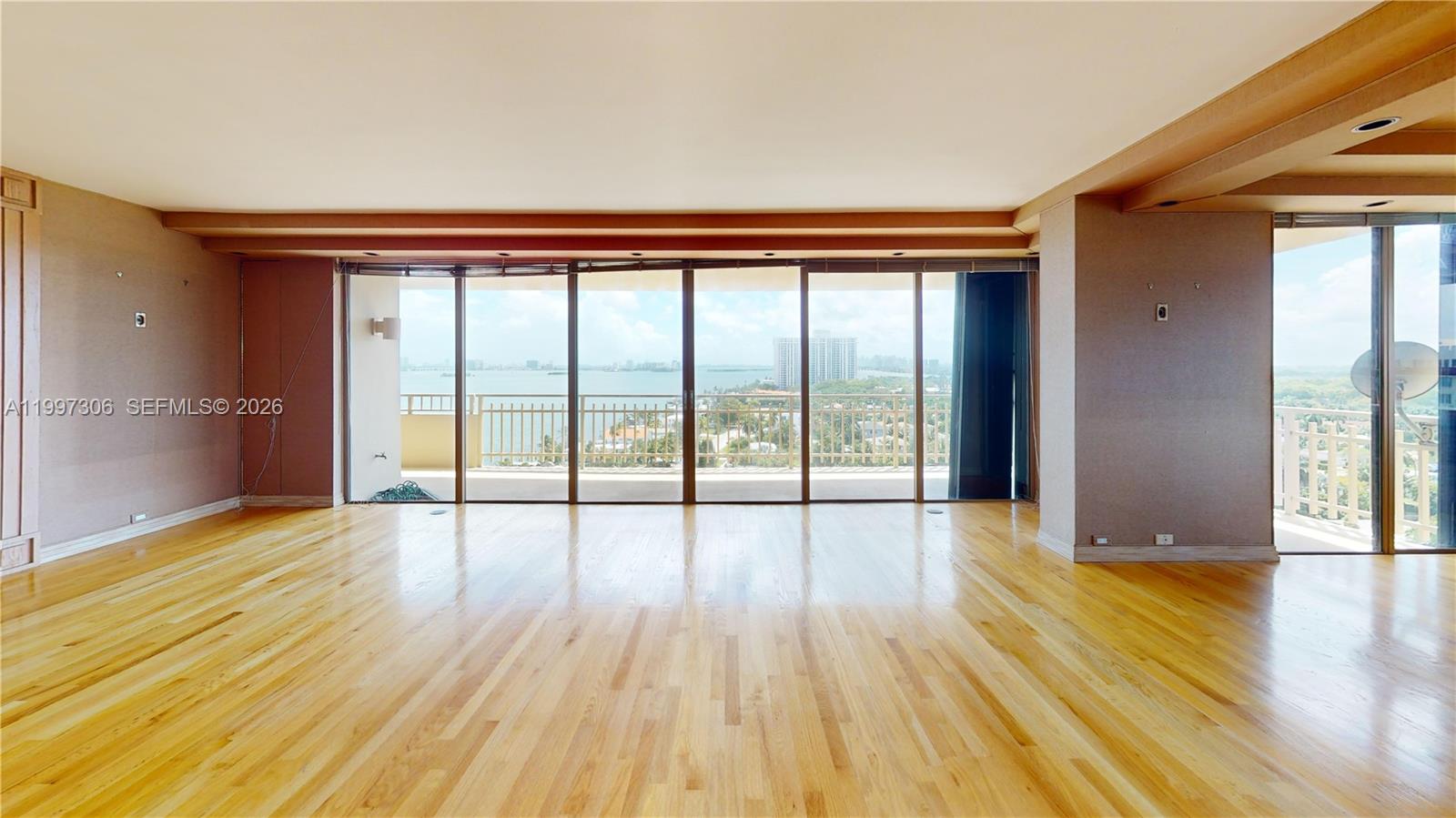 An empty room features light wood flooring, beige walls, and floor-to-ceiling windows overlooking water — 11113 Biscayne Blvd # 1251, Miami FL 33181, MIAMI, FL