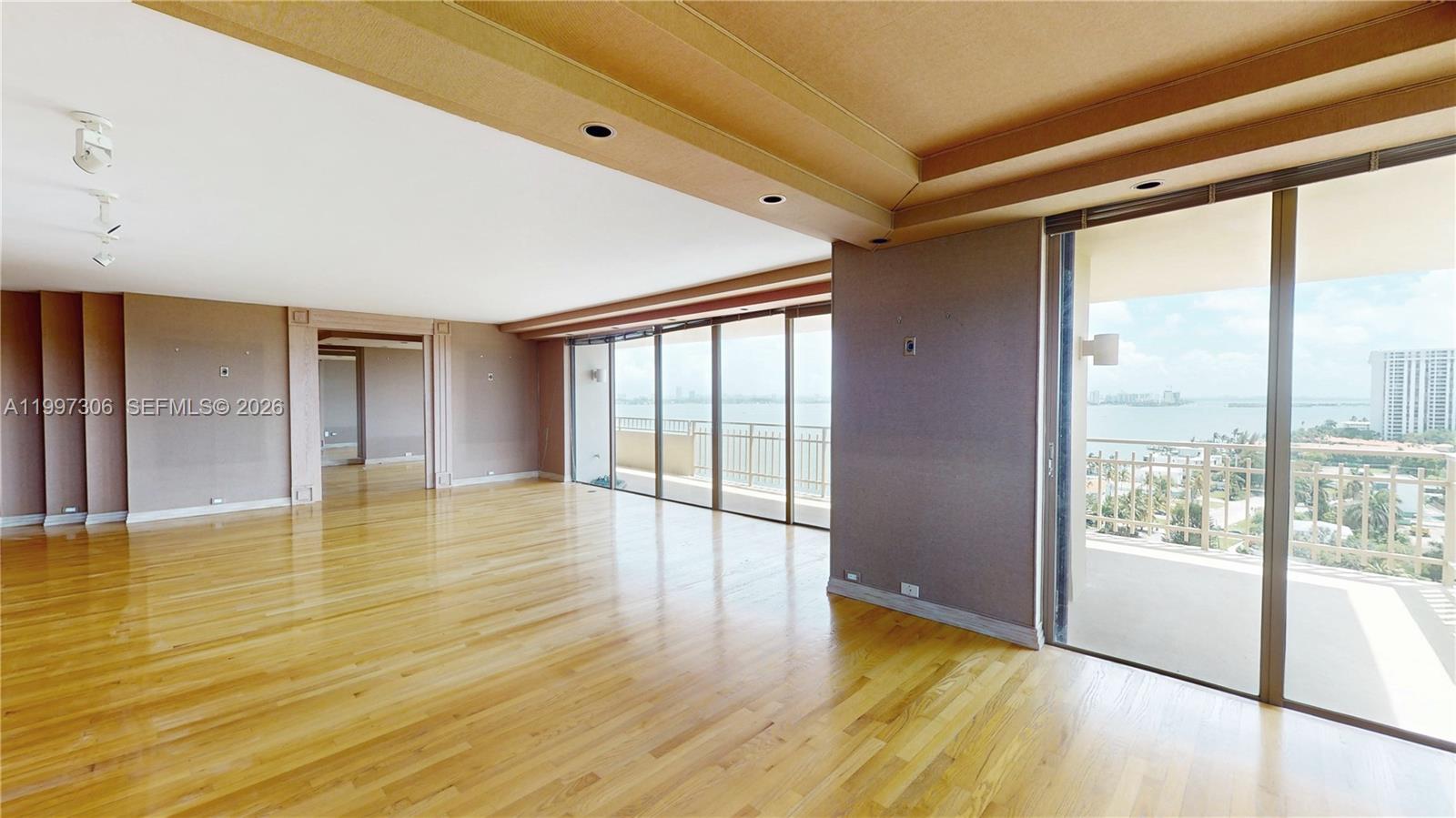 An empty living room features hardwood floors, recessed lighting, and floor-to-ceiling windows overlooking the water — 11113 Biscayne Blvd # 1251, Miami FL 33181, MIAMI, FL