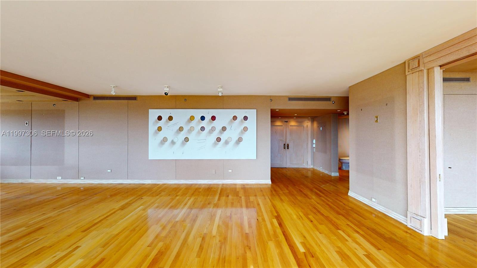 A spacious room features light-colored walls, hardwood flooring, and a large abstract art piece — 11113 Biscayne Blvd # 1251, Miami FL 33181, MIAMI, FL