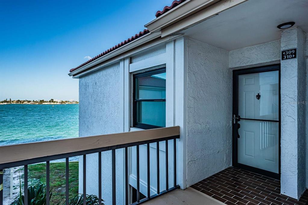An exterior balcony overlooks the water with a white door and a brick floor — 6265 SUN BOULEVARD UNIT 309, ST PETERSBURG, FL