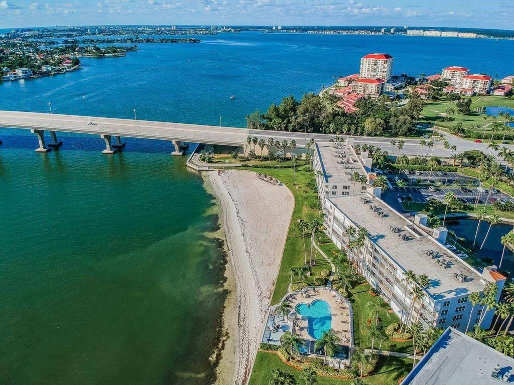 An aerial view shows a waterfront condominium building with a pool next to a bridge — 6265 SUN BOULEVARD UNIT 309, ST PETERSBURG, FL
