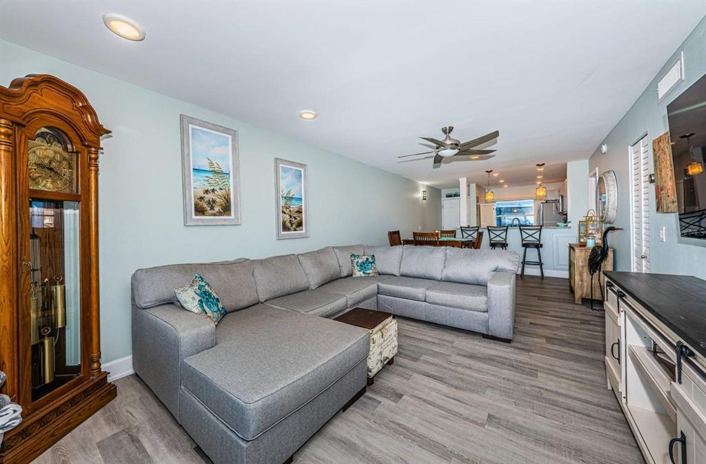 A living room features a large gray sectional sofa, a grandfather clock, and wood-look flooring — 6265 SUN BOULEVARD UNIT 309, ST PETERSBURG, FL
