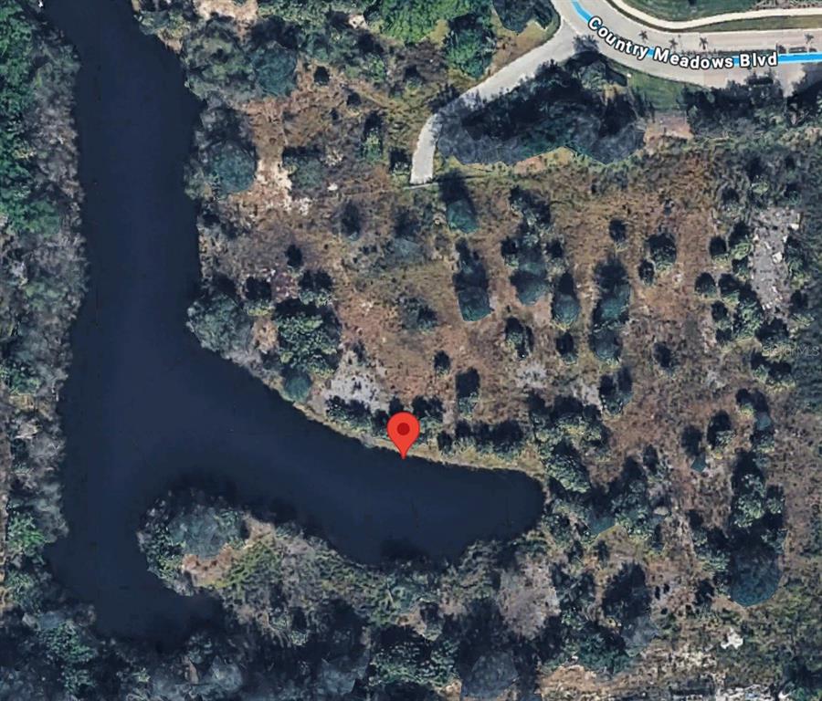 This is an aerial map view showing a body of water and surrounding wooded land — 4187 COUNTRY MEADOWS BOULEVARD, PUNTA GORDA, FL