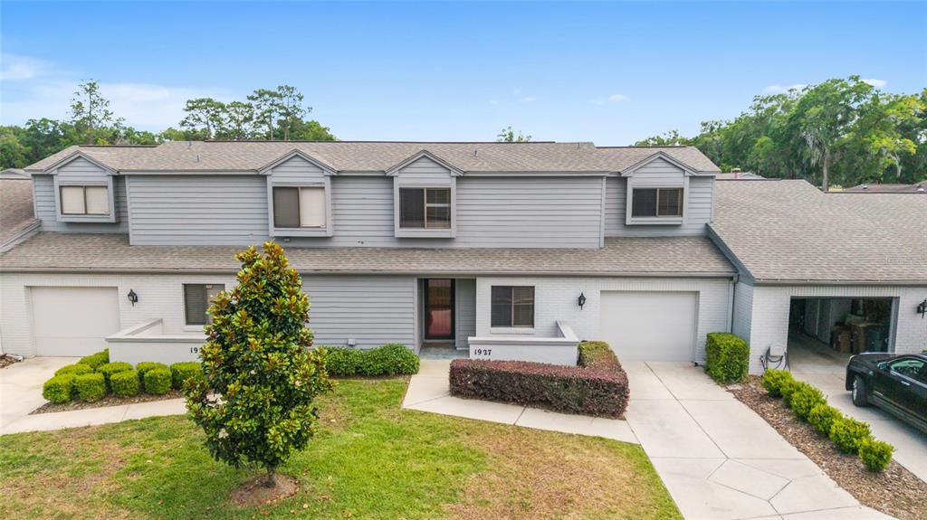 A two-story townhouse with gray siding, brick lower walls, and two attached garages — 1927 SE 37TH COURT CIRCLE, OCALA, FL