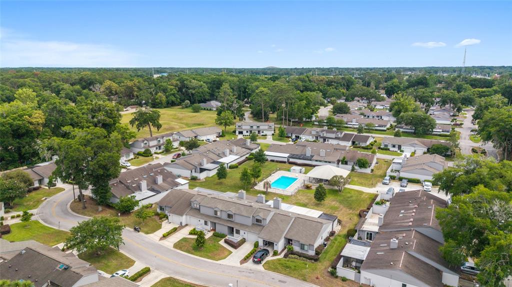 An aerial view shows a residential complex with multiple townhomes, a swimming pool, and trees — 1927 SE 37TH COURT CIRCLE, OCALA, FL
