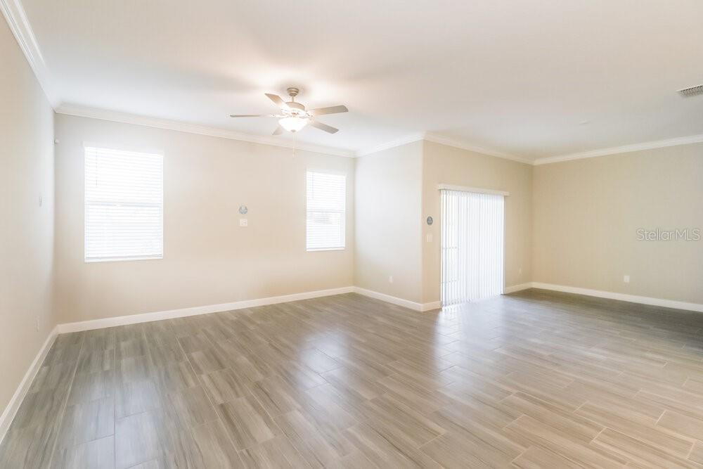 An empty living room features light-colored walls, wood-look tile flooring, and a ceiling fan — 2123 CERULEAN SKY DRIVE, LUTZ, FL