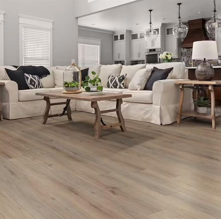 A living room with light wood flooring, a sectional sofa, and an open kitchen background — 4498 RAPALLO AVENUE E, WINTER HAVEN, FL