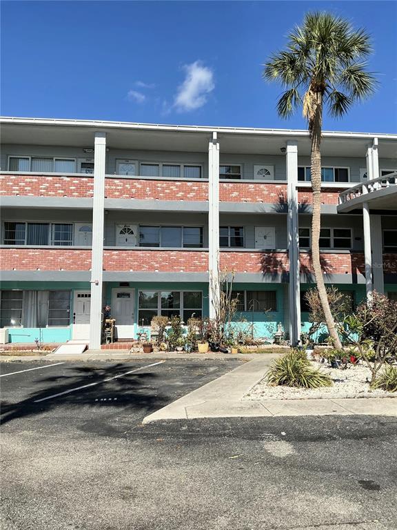 A three-story apartment building features brick siding, white support pillars, and a tall palm tree — 4300 58TH STREET N UNIT 1909, KENNETH CITY, FL