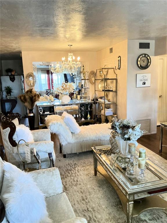 A living room features white tufted furniture, a mirrored coffee table, and a crystal chandelier — 4300 58TH STREET N UNIT 1909, KENNETH CITY, FL