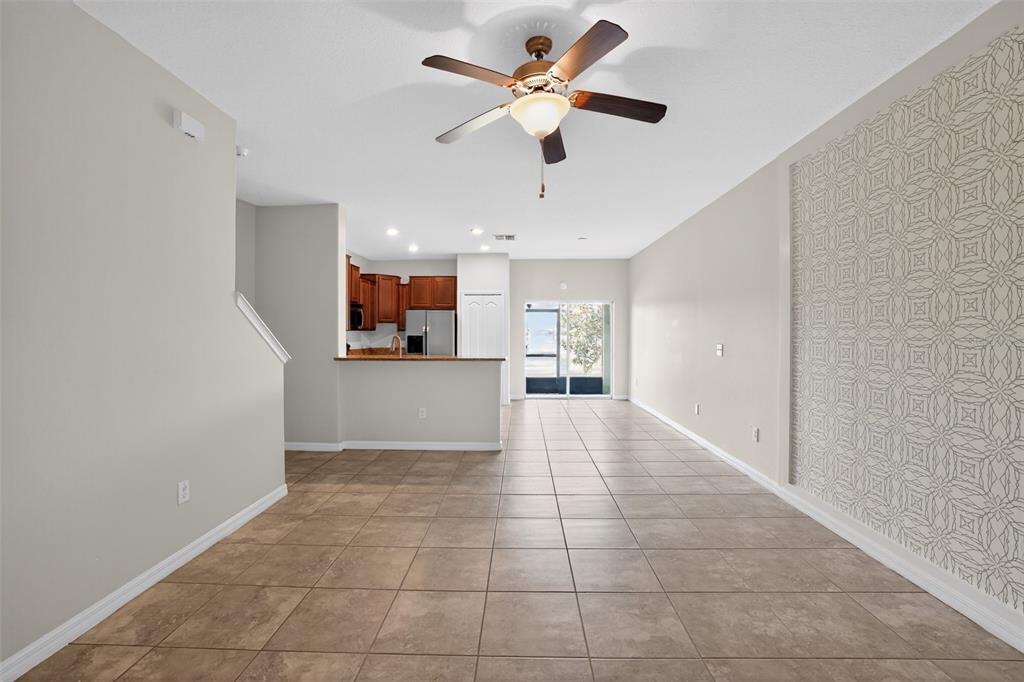 An open-concept living and dining area features tile flooring, a ceiling fan, and wallpaper — 2224 GOLDEN FALCON DRIVE, RUSKIN, FL