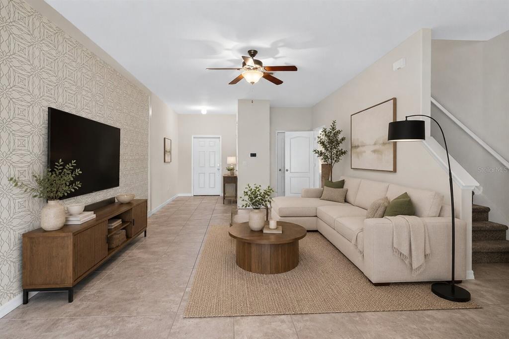 A living room features a patterned accent wall, a sectional sofa, and a television console — 2224 GOLDEN FALCON DRIVE, RUSKIN, FL