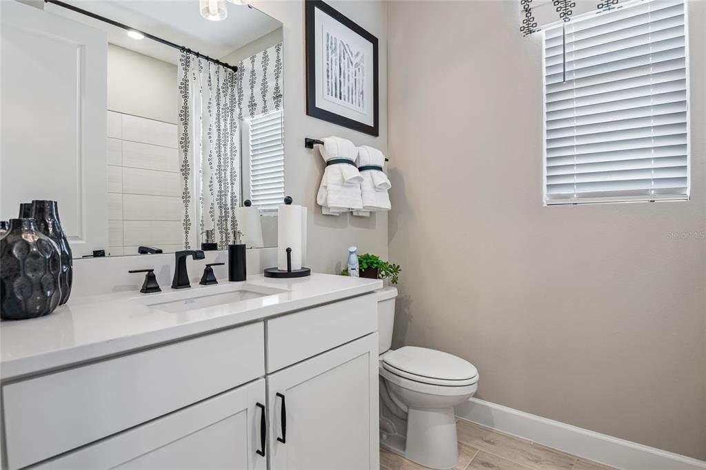A bathroom features a white vanity with a black faucet, a toilet, and a window — 6398 CLOVER STREET, LAKE HAMILTON, FL