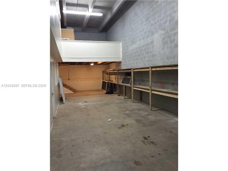 This industrial space features a concrete floor, high ceilings, and built-in wooden shelving units — 10680 NW 123rd St Rd # 104, Medley FL 33178, MEDLEY, FL