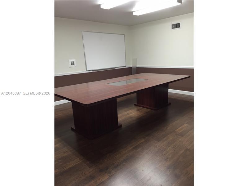 A conference room features a large wooden table, a whiteboard, and dark wood-look flooring — 10680 NW 123rd St Rd # 104, Medley FL 33178, MEDLEY, FL