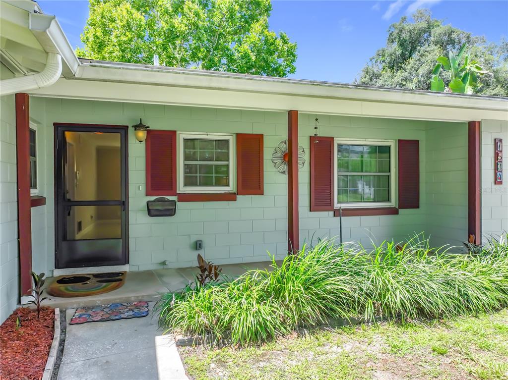 A light green house exterior features a covered porch, red shutters, and a front door — 1534 LEEWAY AVENUE, ORLANDO, FL