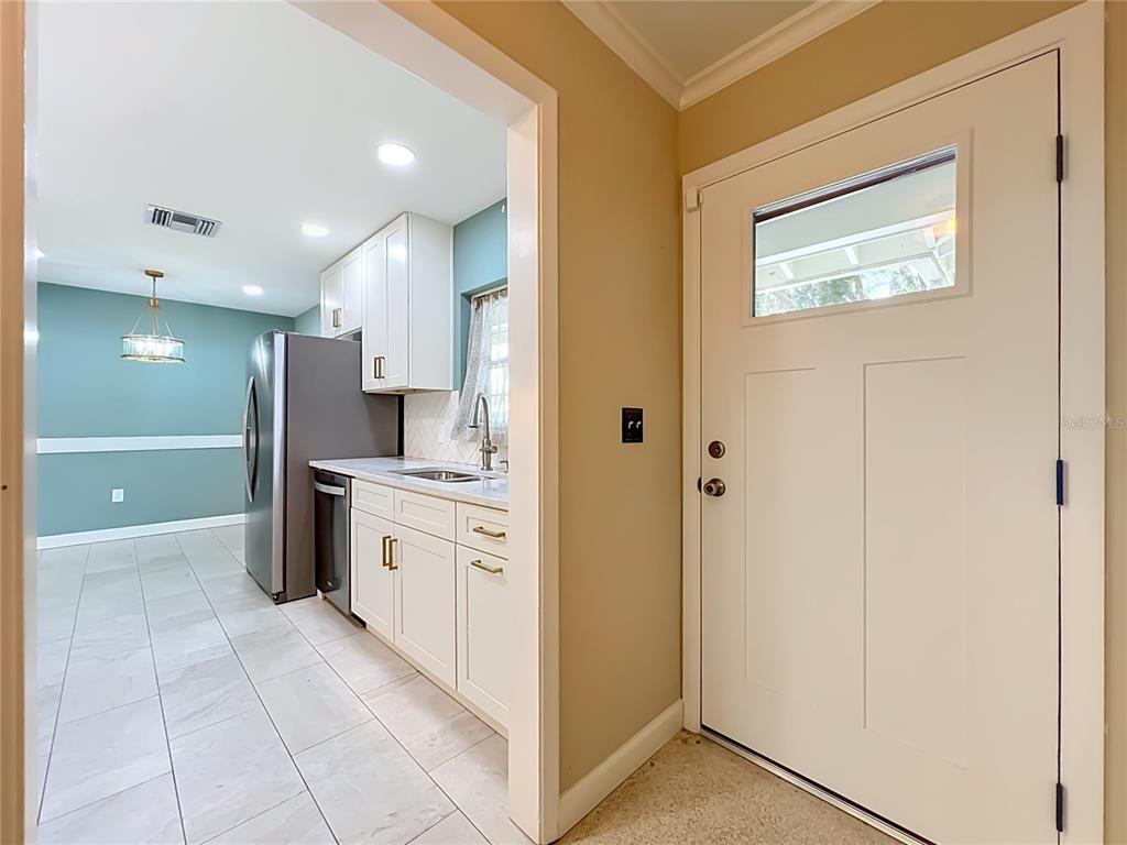 A view from an entryway looking into a kitchen with white cabinets and tile flooring — 1534 LEEWAY AVENUE, ORLANDO, FL