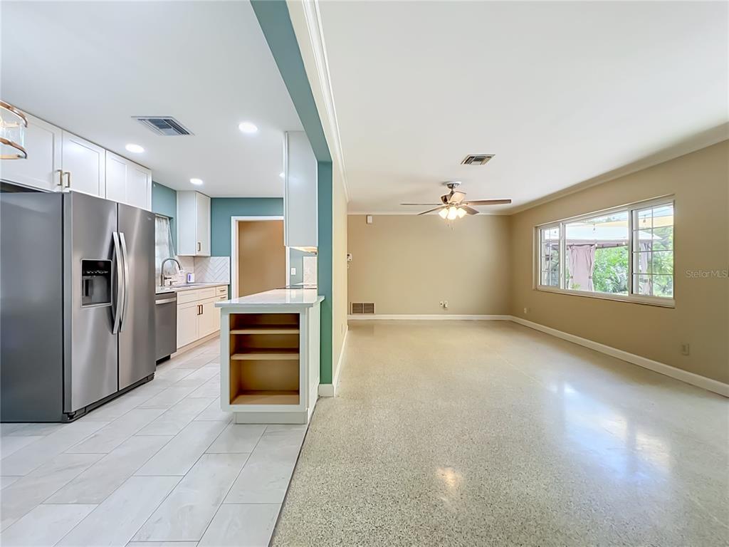 A kitchen with white cabinets and tile floors opens into a large, beige-walled living area — 1534 LEEWAY AVENUE, ORLANDO, FL