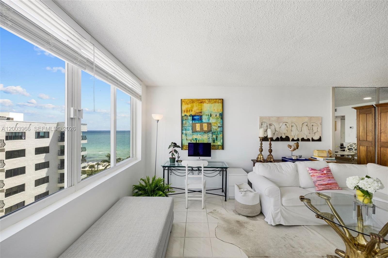 A living room features a desk, white sofa, glass coffee table, and ocean view windows — 5401 Collins Ave # 611, Miami Beach FL 33140, MIAMI BEACH, FL
