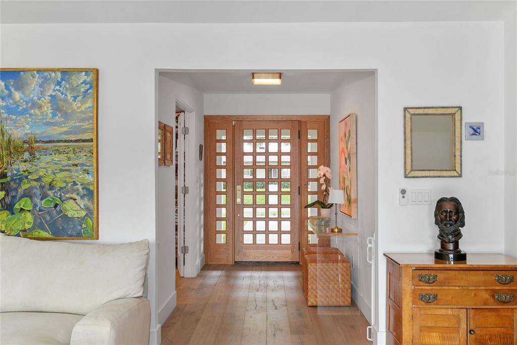 A foyer features a wooden grid-paneled front door, light wood flooring, and a bust sculpture — 220 ADAMS DRIVE, MAITLAND, FL