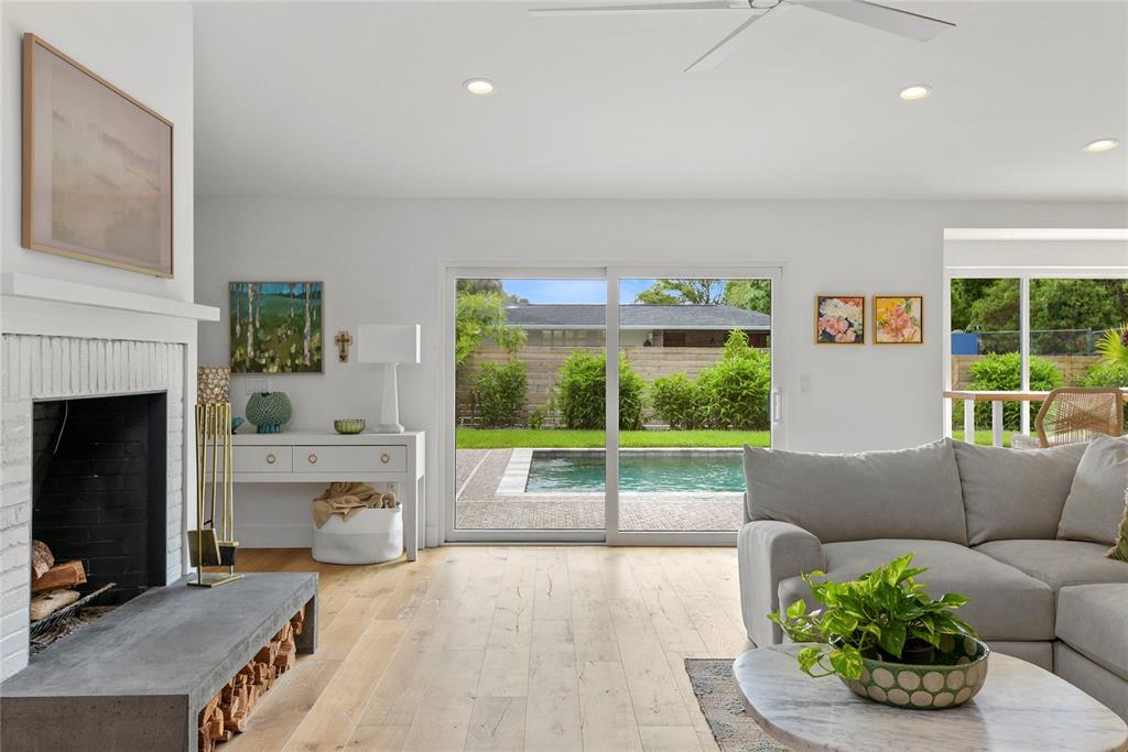A living room features a fireplace, light wood floors, and sliding doors opening to a pool — 220 ADAMS DRIVE, MAITLAND, FL