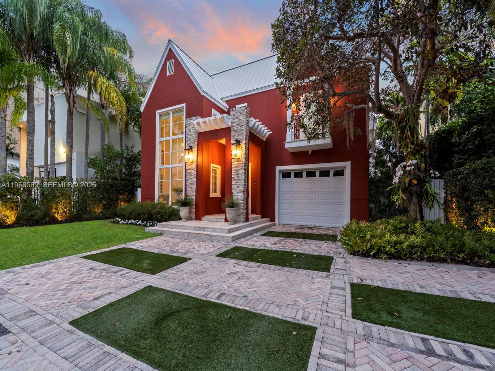 A red two-story house features a stone-accented entryway, a white garage, and a paved driveway — 7218 SW 54th court, Miami FL 33143, MIAMI, FL