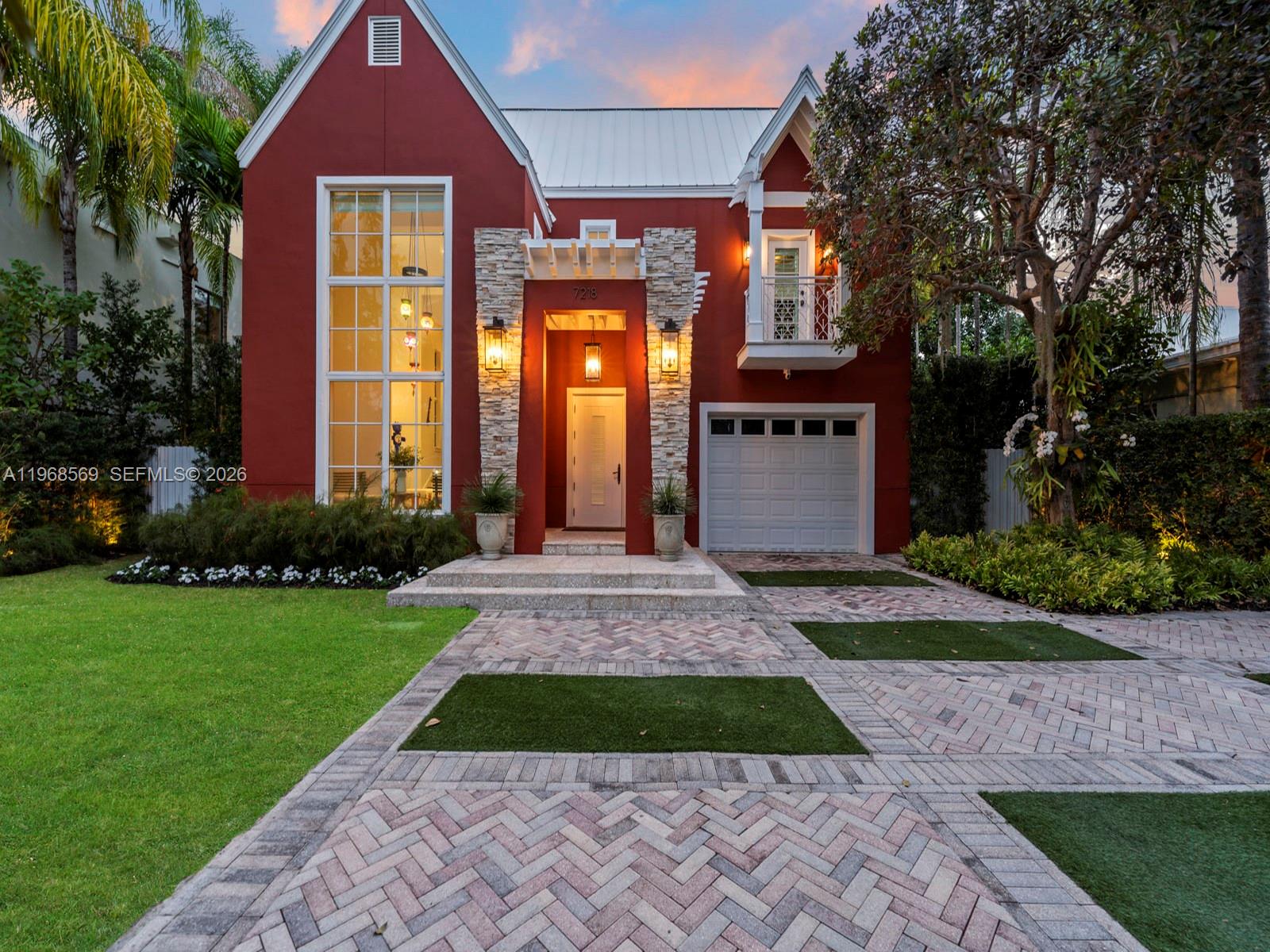 A two-story red house features a stone-accented entryway, a large window, and a paved driveway — 7218 SW 54th court, Miami FL 33143, MIAMI, FL