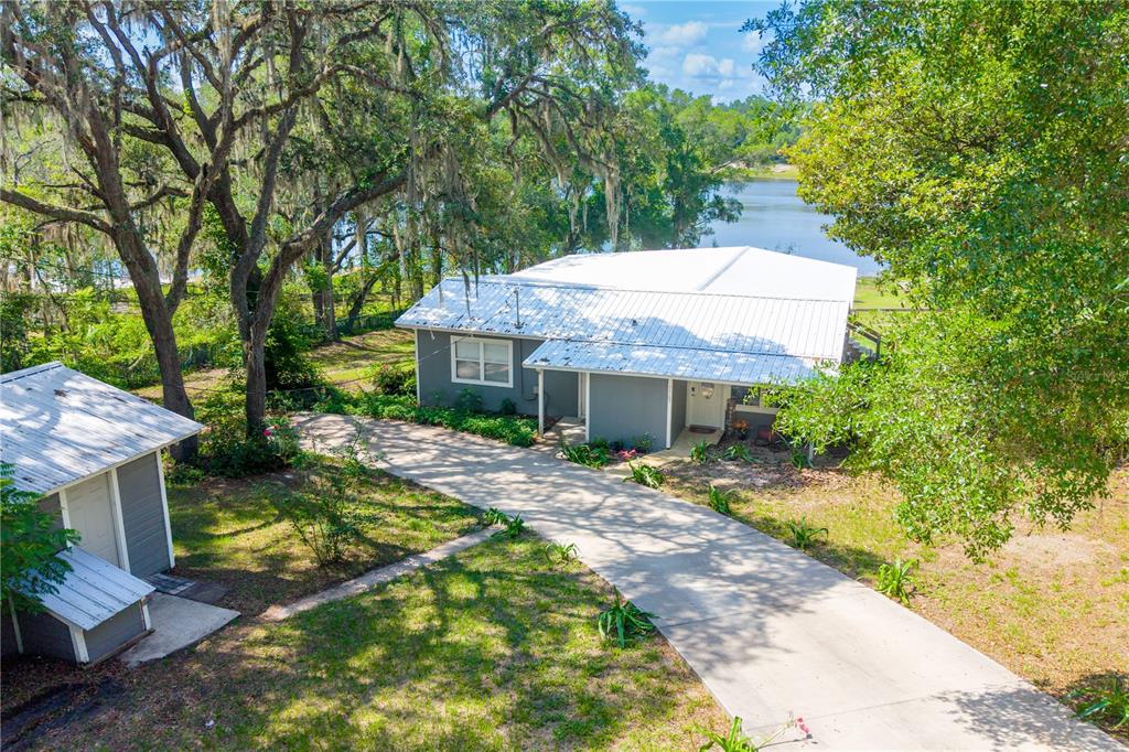 An elevated view of a gray house with a metal roof and a concrete driveway — 7765 TWIN LAKES ROAD, KEYSTONE HEIGHTS, FL