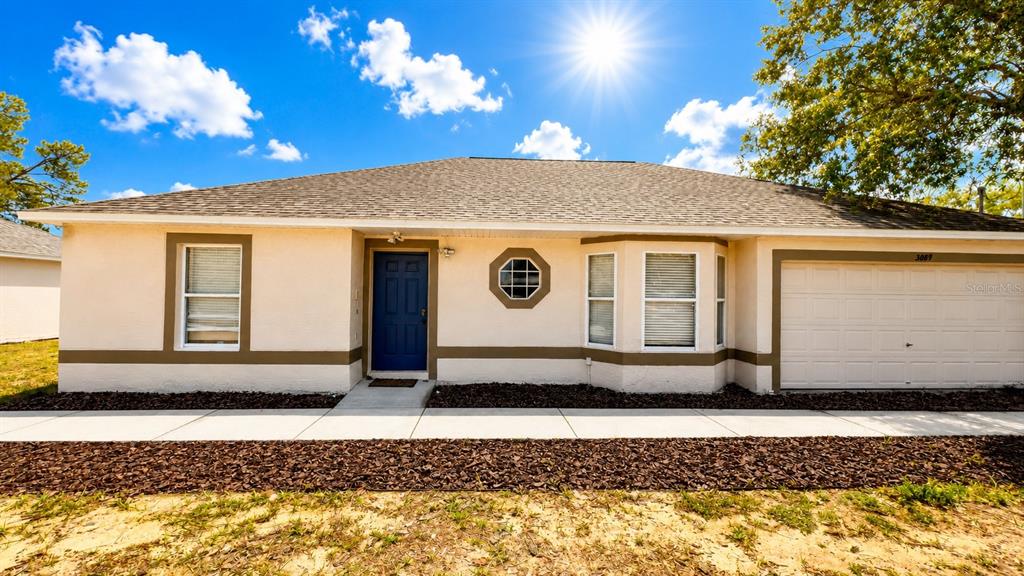 A single-story house with a blue front door, a garage, and a brown shingled roof — 3083 LANDOVER BOULEVARD, SPRING HILL, FL