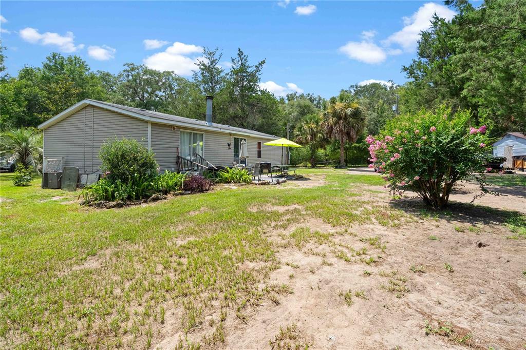 A single-story house with light siding sits on a grassy lot with trees — 151 NE 164TH AVENUE, WILLISTON, FL