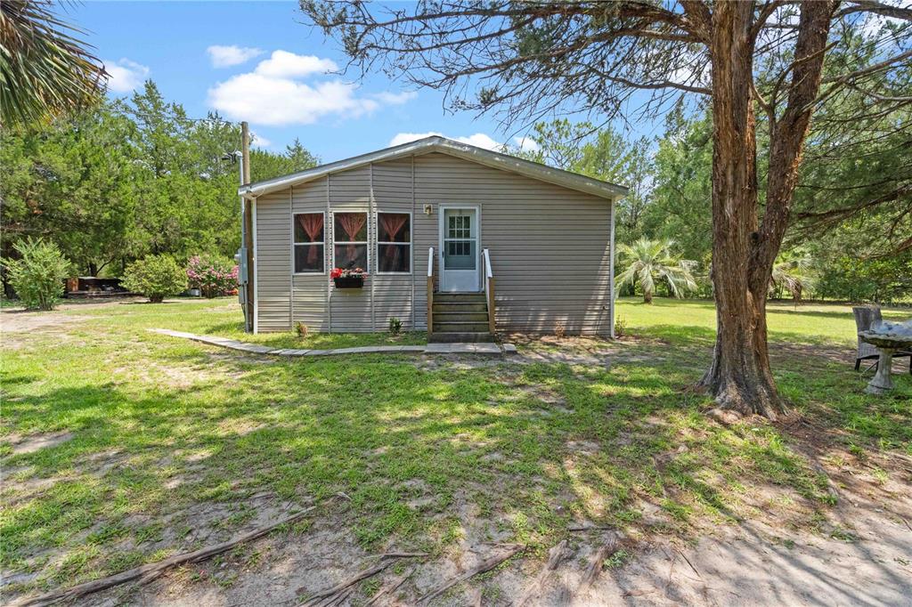 A single-story house with tan siding and a small wooden staircase leading to the entrance — 151 NE 164TH AVENUE, WILLISTON, FL