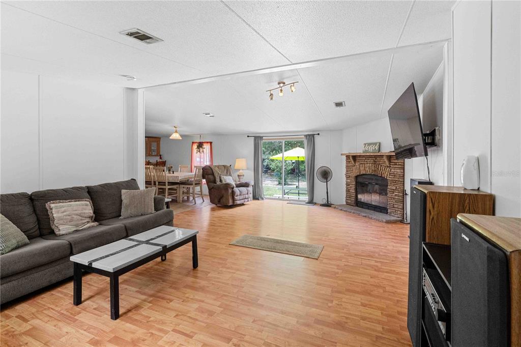 A living room with wood-look flooring, a brick fireplace, and an adjacent dining area — 151 NE 164TH AVENUE, WILLISTON, FL